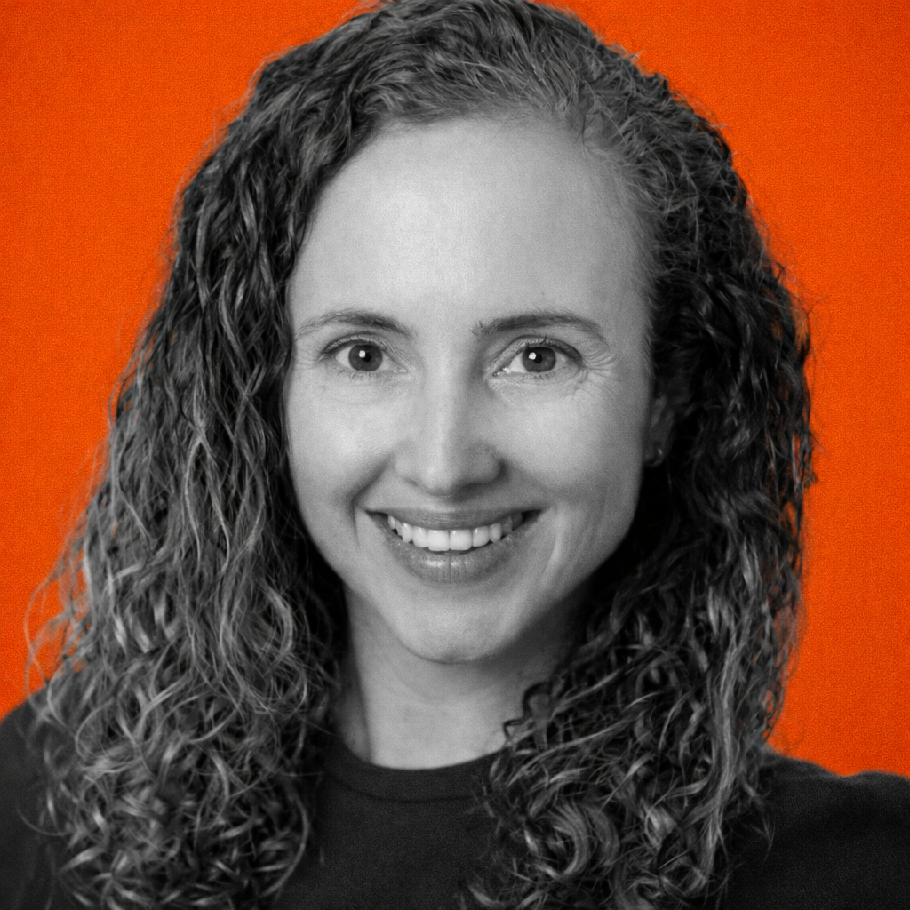 Portrait of a woman with brown hair on a flat gray background.